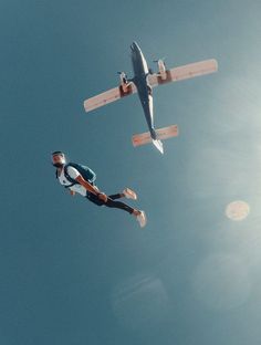 two people are flying in the air with an airplane above them and one person is jumping