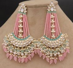 a pair of pink, green and white beaded earrings sitting on top of a mannequin