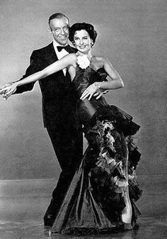 an old black and white photo of two people in formal wear dancing together with their arms around each other