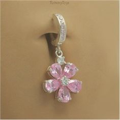 a pink flower charm hanging from the side of a wall with clear crystals on it