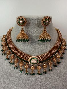 This exquisite piece of craftsmanship comes from our Traditional collection. Finish: 24 grams gold finish Necklace Fastening: Adjustable Dori  Perfect for Indian weddings. Earring jhumka Fastening: Push Back Contains: 1 necklace, 1 pair of earrings Heavy Gold Necklace As Gift, Heavy Gold Necklace For Gifts, Gold Heavy Necklace For Gift, Heavy Gold Jewelry For Celebration, Heavy Gold Necklaces For Festive Occasions, Green Bridal Necklace With 17 Jewels For Ceremonial Occasion, Bollywood Style Round Necklaces For Celebrations, Gold Kundan Chandbali Necklace, Heavy Gold Temple Jewelry