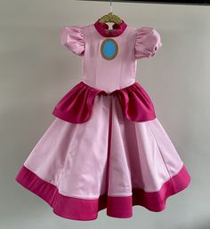 a pink princess dress hanging on a clothesline with a blue circle in the center