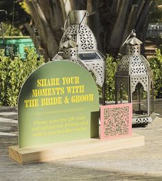 two metal lanterns sitting on top of a wooden table next to a sign that says share your moments with the bride and groom