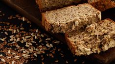 sliced loaf of bread sitting on top of a wooden cutting board next to seed seeds