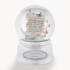 a glass snow globe with a poem in it on a white base and pink flowers