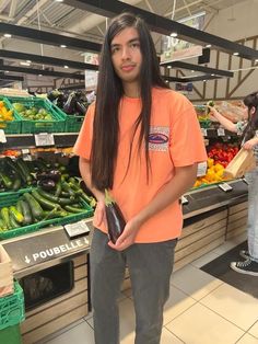 a man in an orange shirt standing next to vegetables