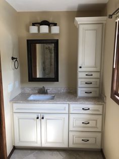 a bathroom with white cabinets and marble counter tops