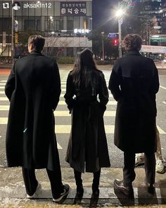 three people standing at an intersection waiting for the light to turn on and go down