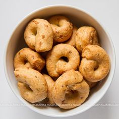 a white bowl filled with doughnuts on top of a table