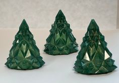 three green glass trees sitting on top of a table