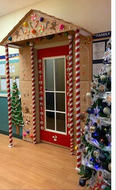 a decorated christmas tree in front of a red door with candy canes on it