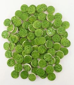 a pile of green buttons sitting on top of a white table