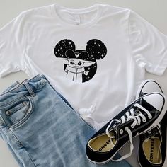 a white shirt with an image of mickey mouse on it and some denim shorts next to it