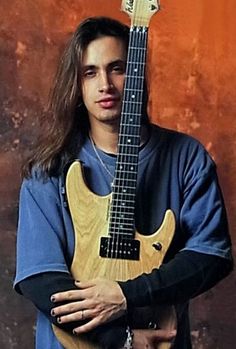 a man with long hair holding an electric guitar in his hands and posing for the camera