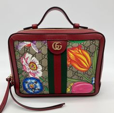 Gucci GG Supreme Flora Small Ophidia Camera Bag in new without tag condition. Monogram canvas with beautiful floral web print throughout trimmed with red leather and brass hardware. Top handle and removable striped canvas shoulder strap easily convert between hand and shoulder styles. Double zip closure opens 3 sides to a beige microsuede interior with one slit and one zipped side pockets. New unused condition. Purchase includes a dust cover. Measurements: 10x8x3" 2" handle 21.5" shoulder strap Leather And Brass, Gucci Ophidia, Vuitton Bag, Bags Designer Fashion, Dust Cover, Exclusive Bag, Brass Hardware, New Bag, Monogram Canvas