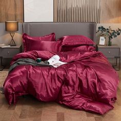 a bed with a red comforter and pillows on top of it in a room