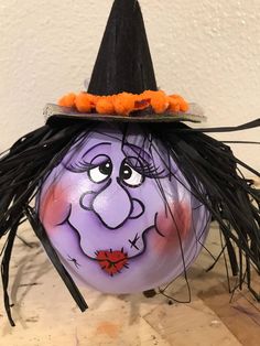 a purple pumpkin with a witch's hat painted on it sitting on top of a wooden table