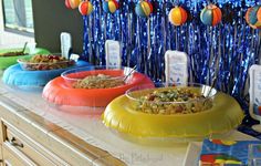 three bowls filled with food sitting on top of a counter next to balloons and streamers