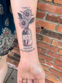 a person with a tattoo on their arm holding a flower in a mason jar that says,