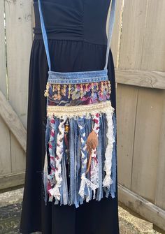 a woman's apron made out of old jeans and other fabric material, hanging on a wooden fence