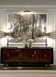 a living room with two lamps and a large painting on the wall above it's console table