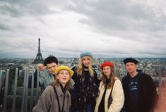 a group of young people standing next to each other in front of the eiffel tower