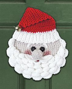 a close up of a knitted santa clause on a green door with a red and white hat