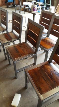 four wooden chairs sitting next to each other on top of a cement floor in a room