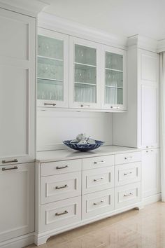 a kitchen with white cabinets and glass doors