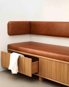 a brown leather bench sitting next to a wall with drawers on it's sides