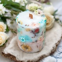 a white candle sitting on top of a table next to flowers