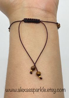 This beautifully handmade bracelet is made of round medium 4mm Brown tiger's eye beads sectioned by small gold colored beads and with a glass evil eye bead (choice of color). The bracelet is made with brown thread string and are adjustable to fit most wrists as it has a sliding knot drawstring to adjust. These are a great accessory for everyday wear for both men and women. Tiger's eye crystal is a beautiful bead with bands of brown and golden colors. It is believed that this stone helps to maint Brown Beaded Bracelets With Gold Beads As Gift, Gift Brown Beaded Bracelets With Gold Beads, Adjustable Brown Jewelry With Gold Beads, Adjustable Spiritual Beaded Bracelets With Gold Beads, Adjustable Brown Braided Bracelets For Healing, Spiritual Brown Beaded Friendship Bracelets, Brown Beaded Spiritual Friendship Bracelets, Brown Beaded Bracelet With Sliding Knot For Gift, Spiritual Brown Friendship Bracelet With Sliding Knot