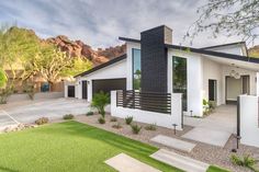 a modern house in the desert with mountains in the backgrouds and grass