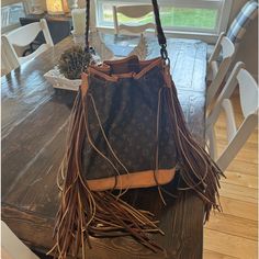 a brown purse sitting on top of a wooden table next to a white chair and window