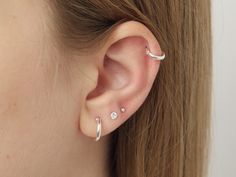 a woman's ear with three piercings on the top and one in the middle