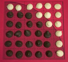 a board game with pieces of chocolate and white frosting on the top, sitting on a red surface