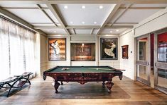 a pool table in the middle of a room with two benches and pictures on the wall