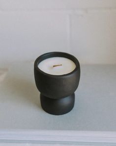 a black candle holder sitting on top of a white table next to a stack of books