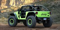 a green jeep driving down a dirt road in front of a rocky mountain side with the word jeep written on it