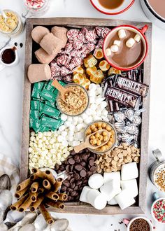 a tray filled with candy, marshmallows, and other treats on top of a table