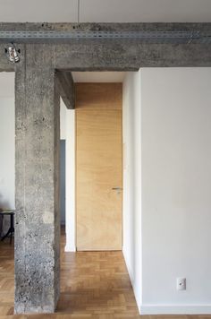 an empty room with a wooden door and hard wood flooring on the side wall