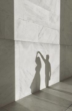 the shadow of a person reaching up against a wall