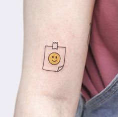 a small smiley face tattoo on the arm