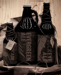 three bottles of beer sitting on top of a table next to some paper bags and twine