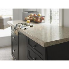 a kitchen island with some fruit on it and a basket of apples in the background