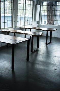 an empty room with several tables and windows in it, all lined up against the wall