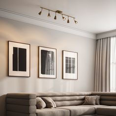 a living room filled with furniture and framed pictures on the wall above it's windows