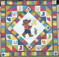 a teddy bear quilt hanging on a clothes line in front of a wooden fence with an american flag