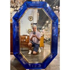 a man sitting in front of a blue mirror