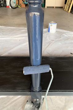 a large blue vase sitting on top of a wooden table next to a metal pipe